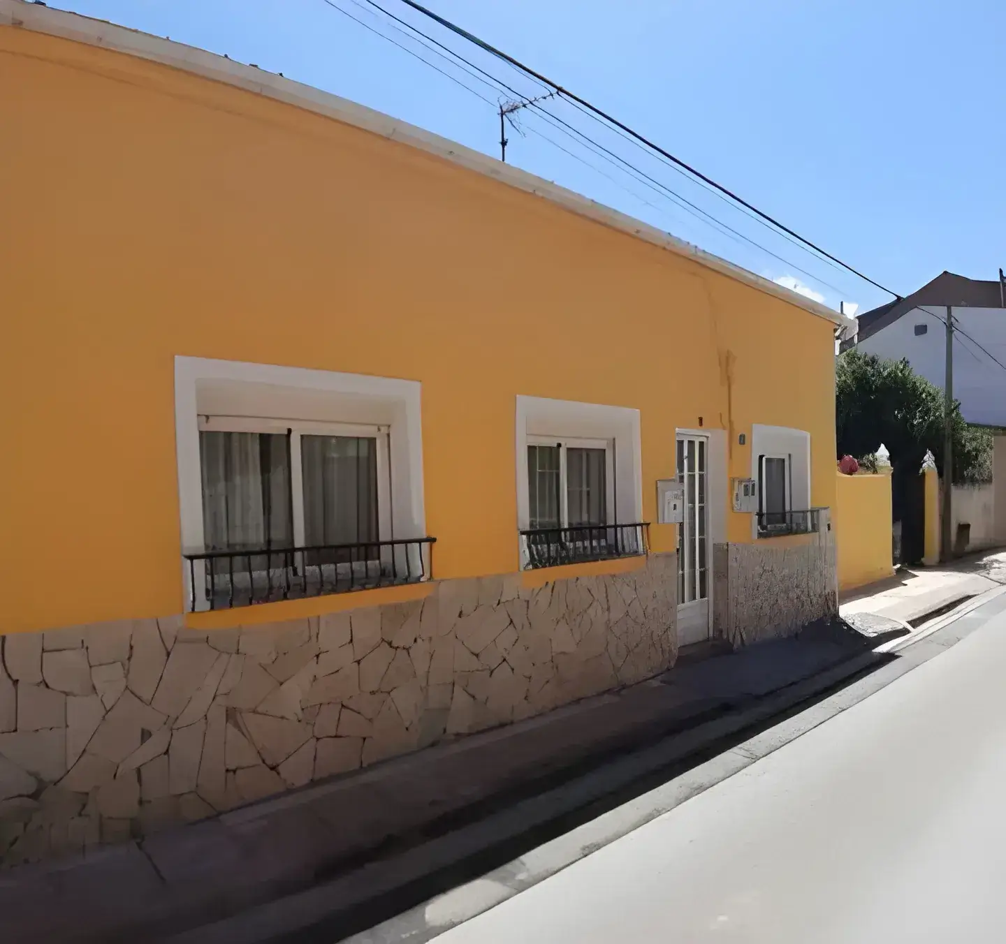 Los Pintores Huelva Fachada de casa tradicional pintada en color amarillo con zócalo de piedra
